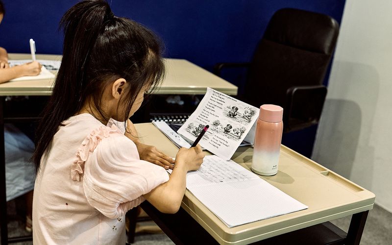 A parent and primary-school child reading an English book together at GL Academy in Kuala Lumpur